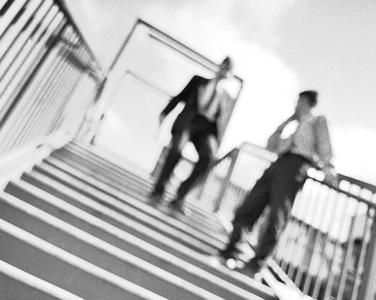 Two men walking down stairs, out of focus, black and white