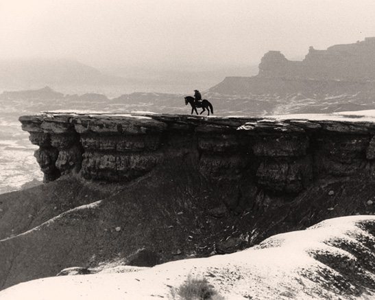 Photo of a man on a horse on the edge of a butte