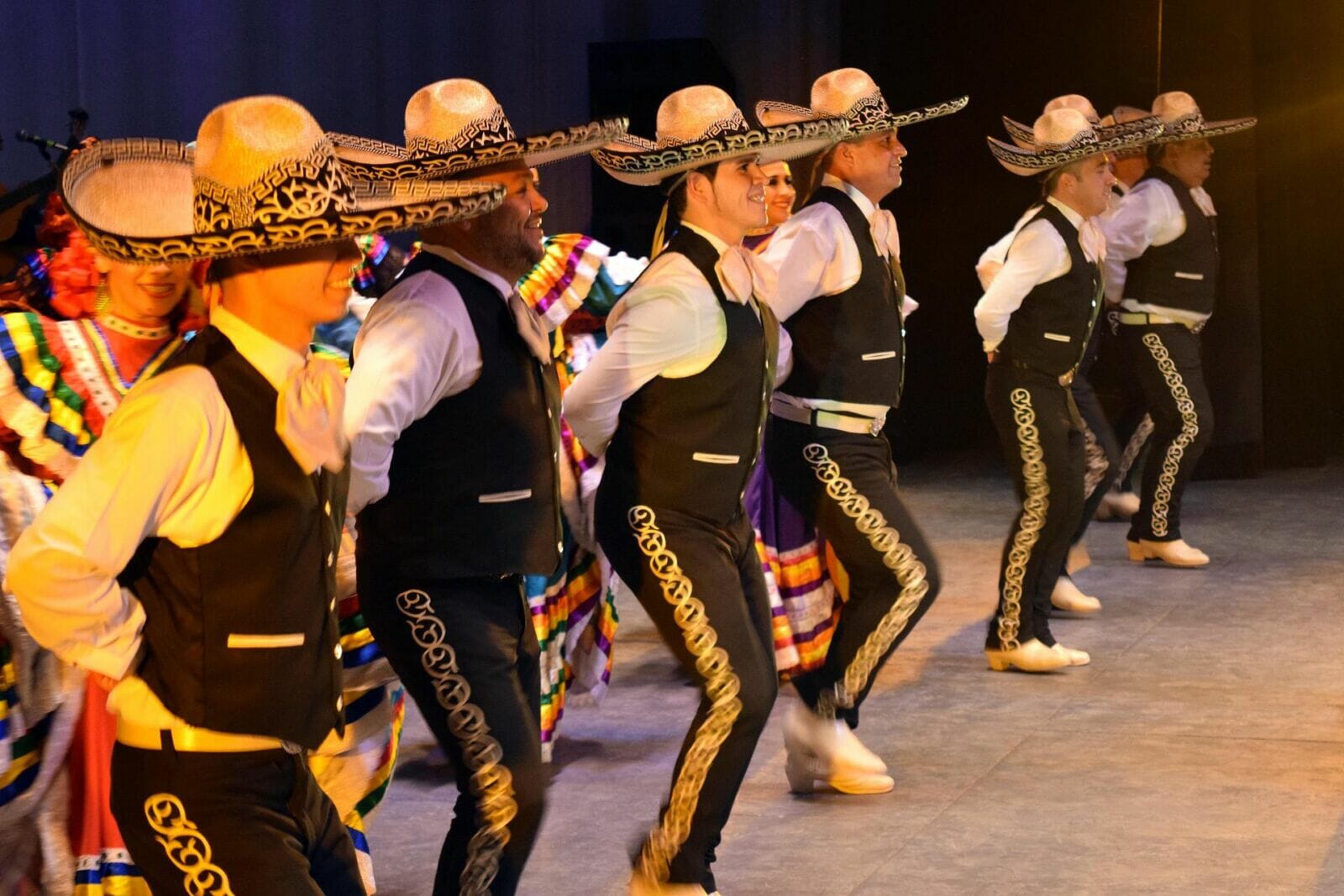 Five Mariachi dancers in black attire dance on stage for Cinco de Mayo.