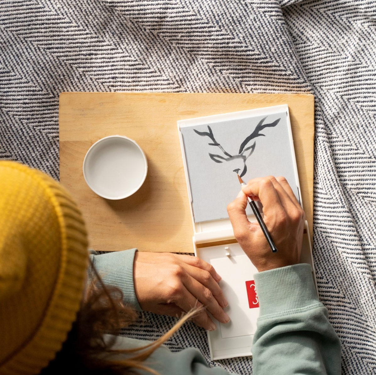 Woman draws image of a deer with paintbrush and water on Buddha Board.