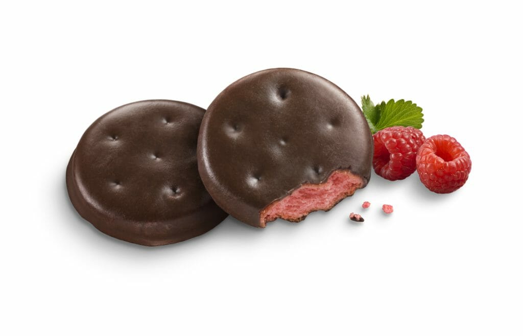 Chocolate covered round Girl Scout cookies filled with raspberry with two raspberries.
