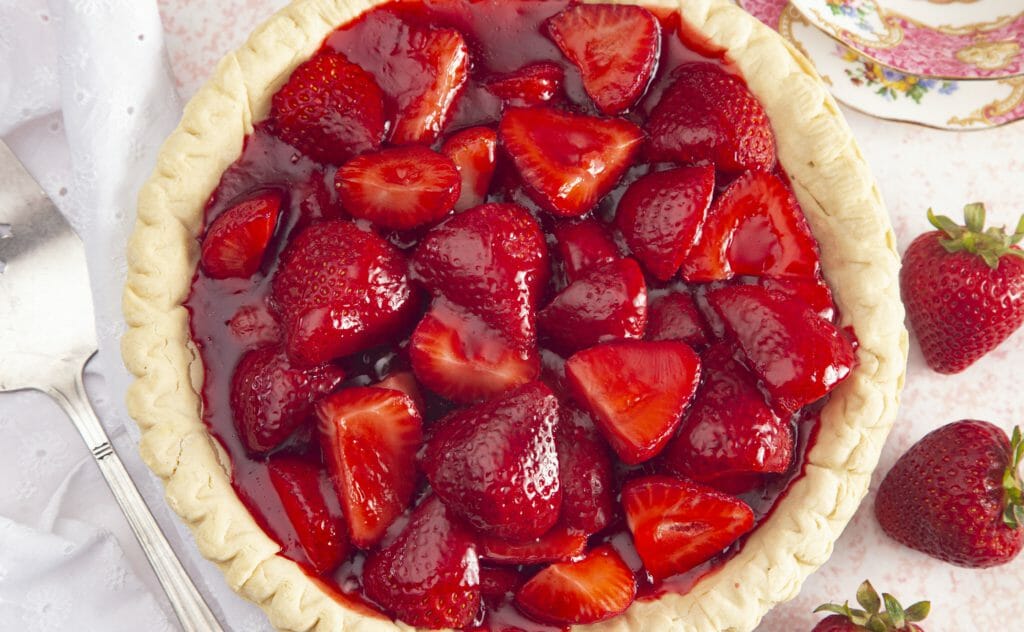 Fresh whole strawberries with glaze inside a light-colored pie crust.