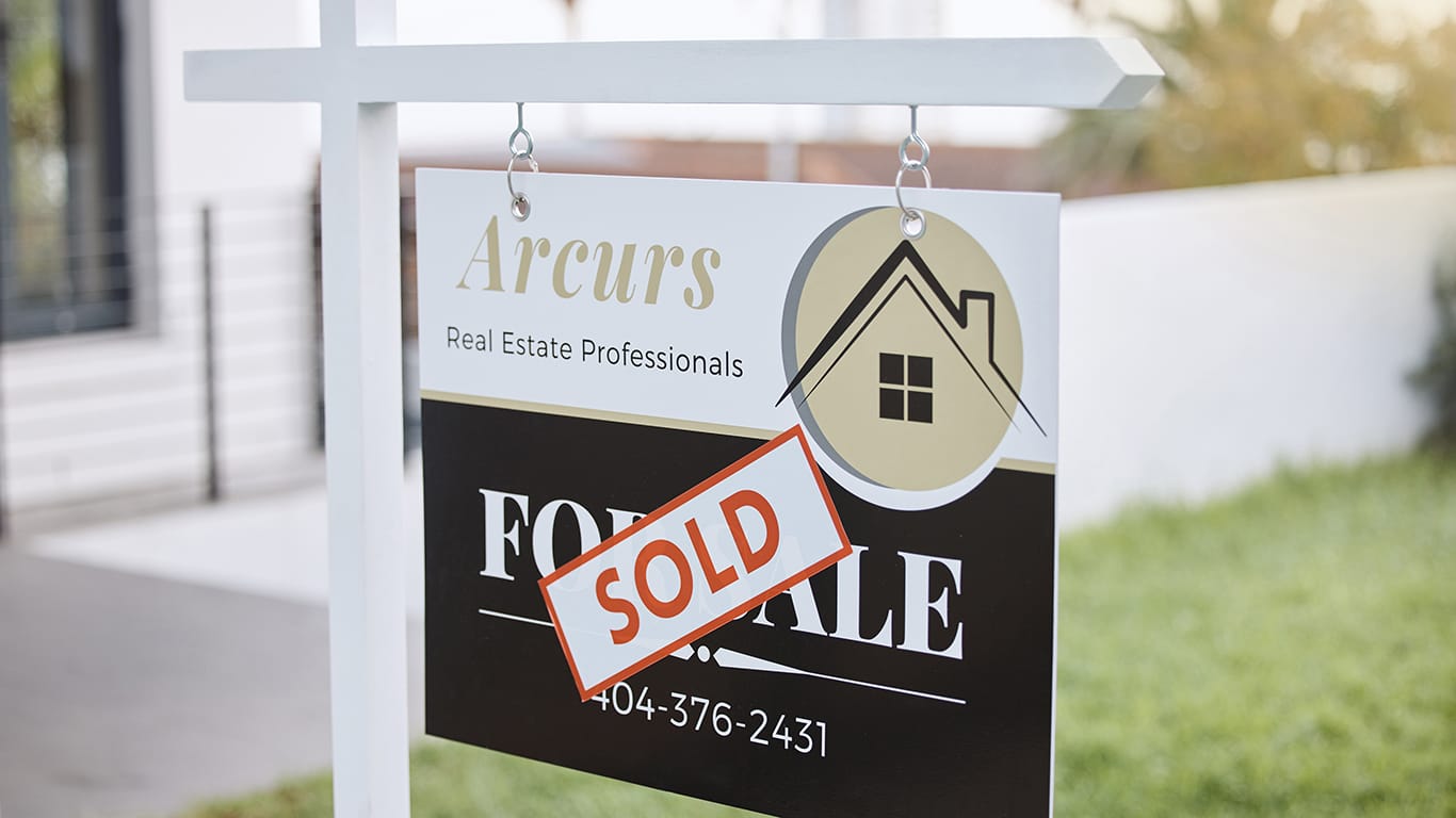 Shot of for sale sign with a sold sticker outside a house.