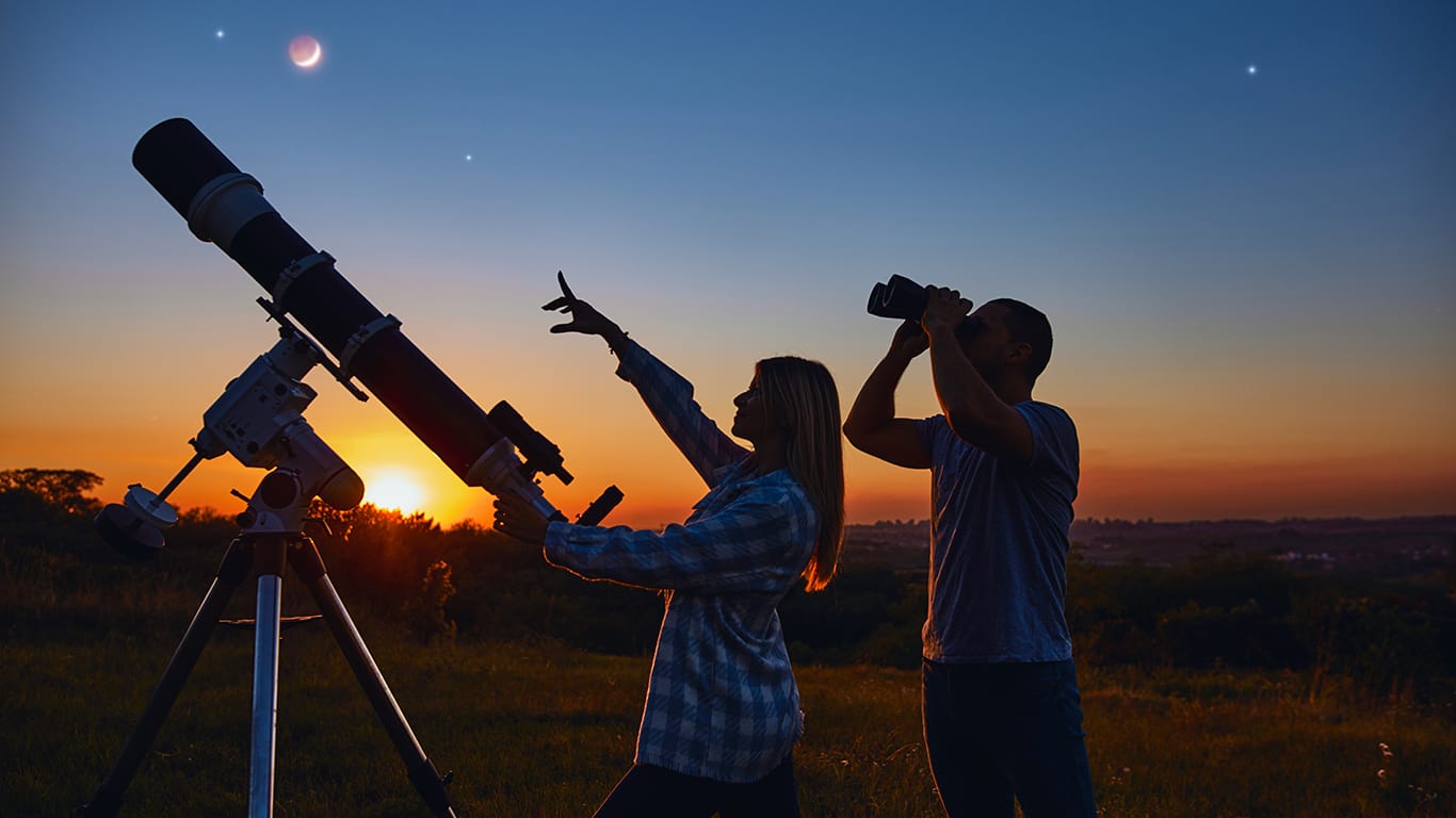 Couple stargazing together with a astronomical telescope.