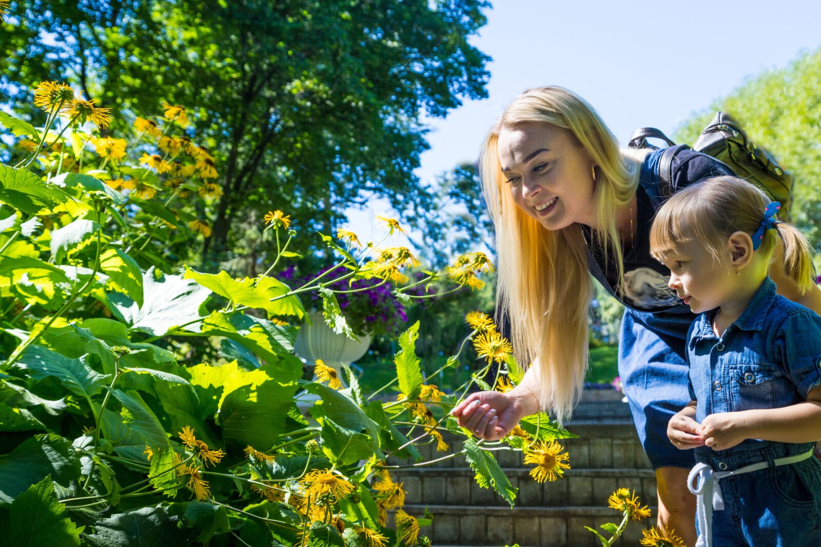 Cute blonde woman and her daughter in the park. Family with happy emotion. Horizontal portrait little girl and her mom walking outdoor together.