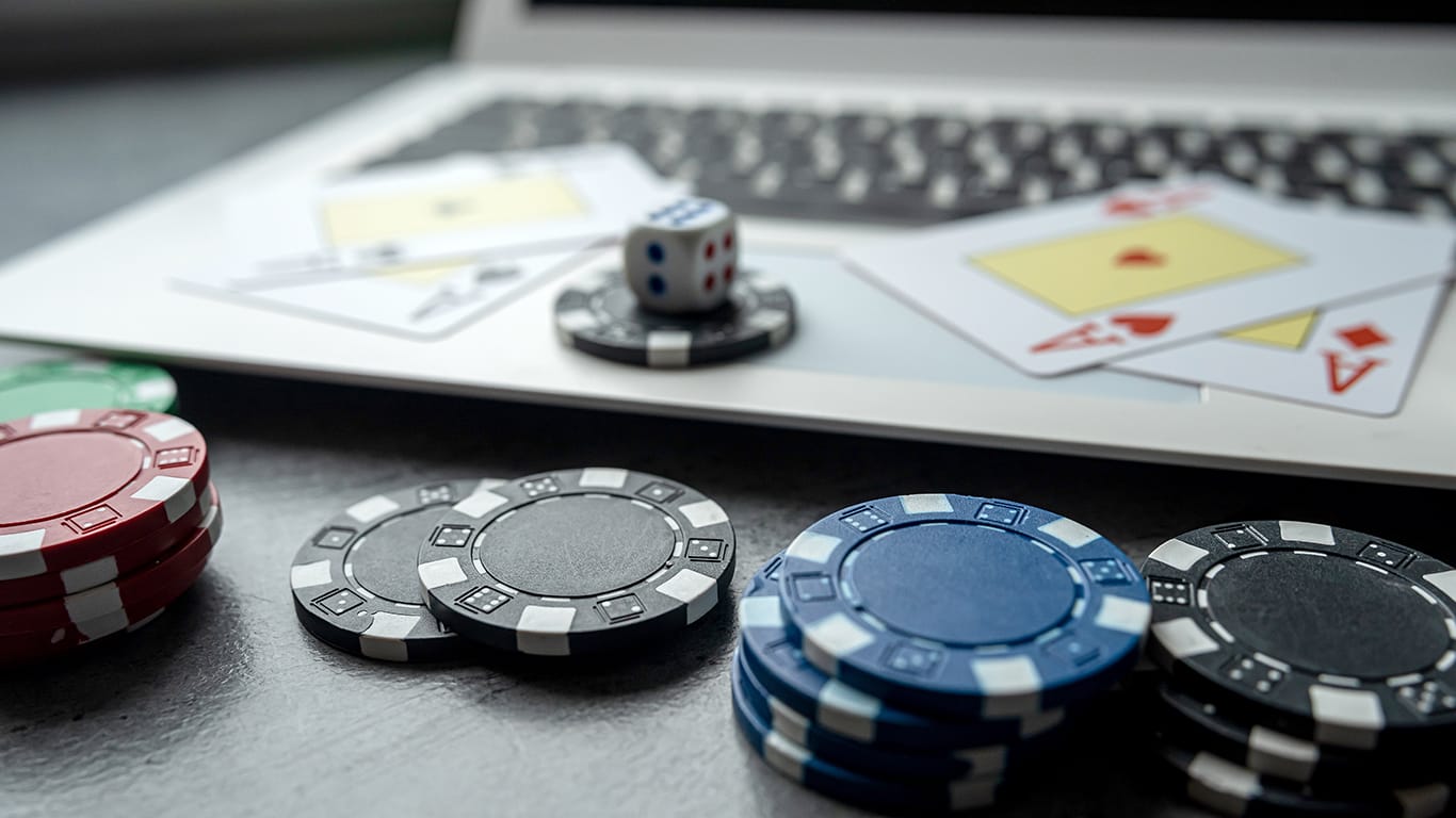 Casino chips and playing cards on laptop notebook.