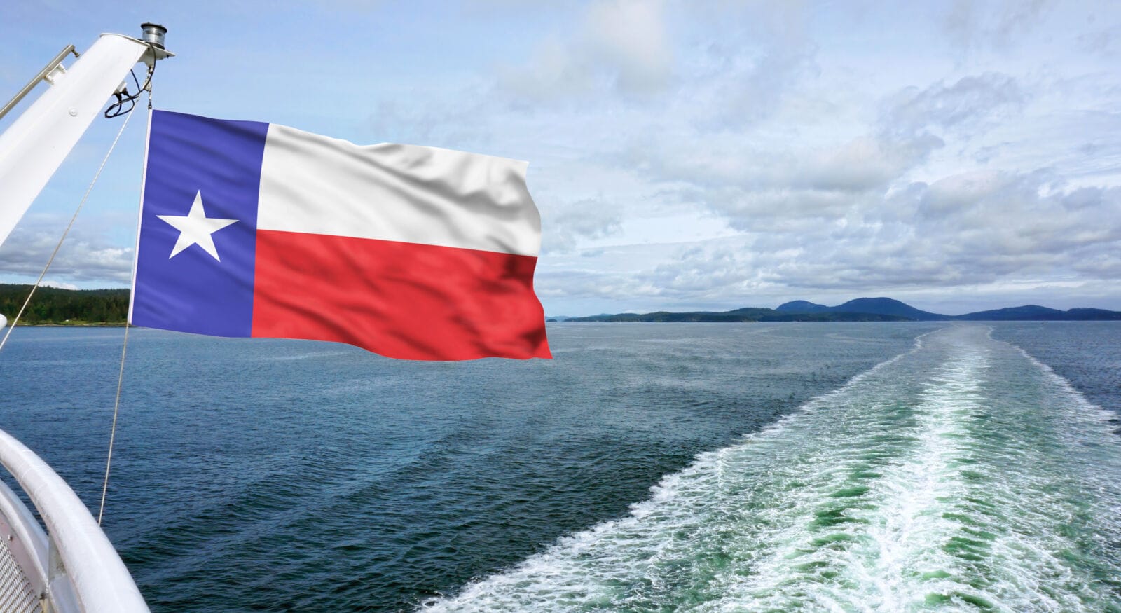 Texas flag flying high against the blue water waves.