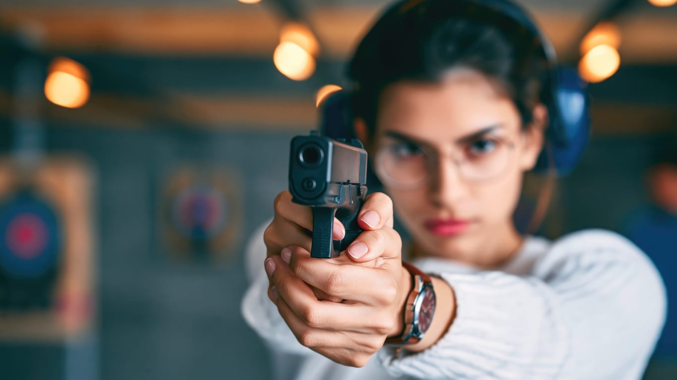 Young Woman Practicing Shooting with Handgun at Indoor Firing Range.