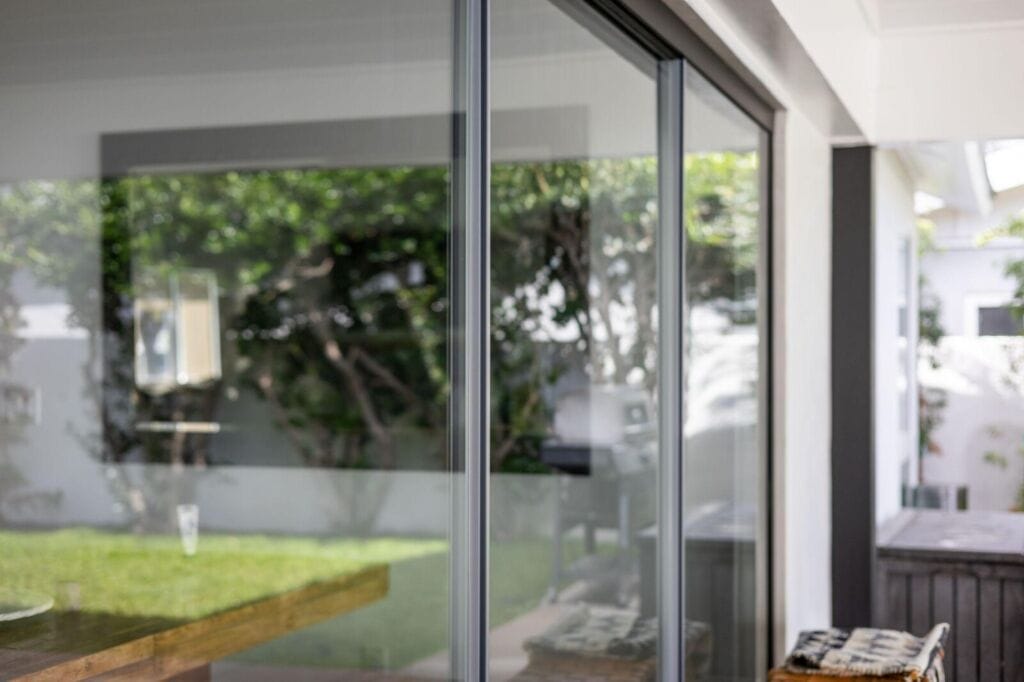 Frameless sliding glass wall by Crystalia Glass opened between a dining room and covered patio.