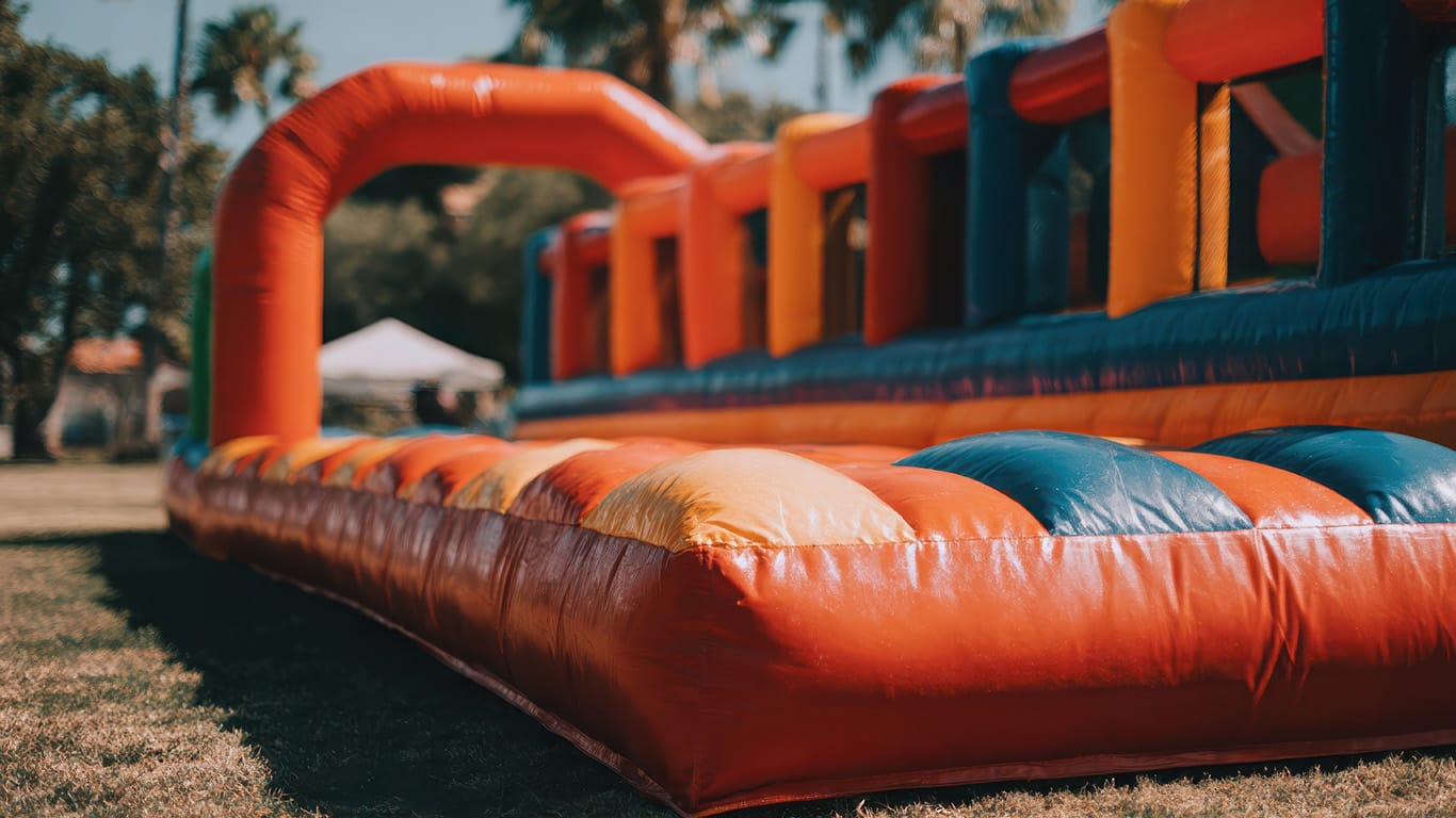 A vibrant and colorful inflatable obstacle course bouncy castle sits ready for outdoor fun, perfect for children's parties and events, providing hours of active entertainment.