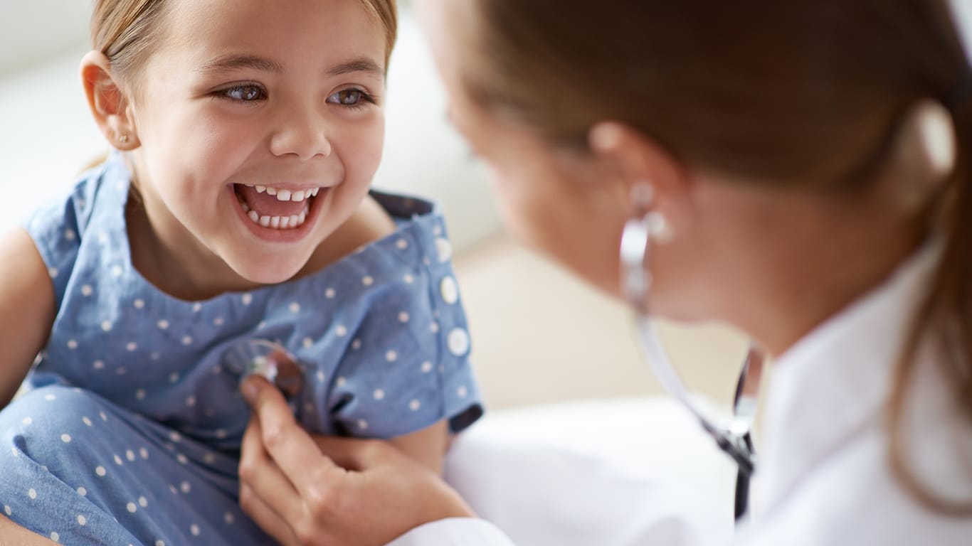 Happy child, girl and stethoscope of doctor for medical consulting, healthy lungs and listening to heartbeat. Face of laughing kid, pediatrician and chest assessment for healthcare analysis in clinic.