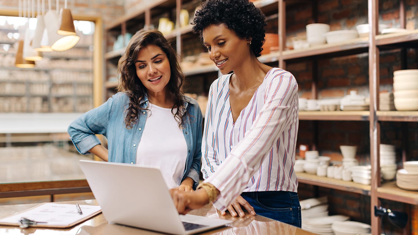 Young female ceramists using a laptop while working together. Two female entrepreneurs managing online orders in their store. Happy young businesswomen running a successful small business together.