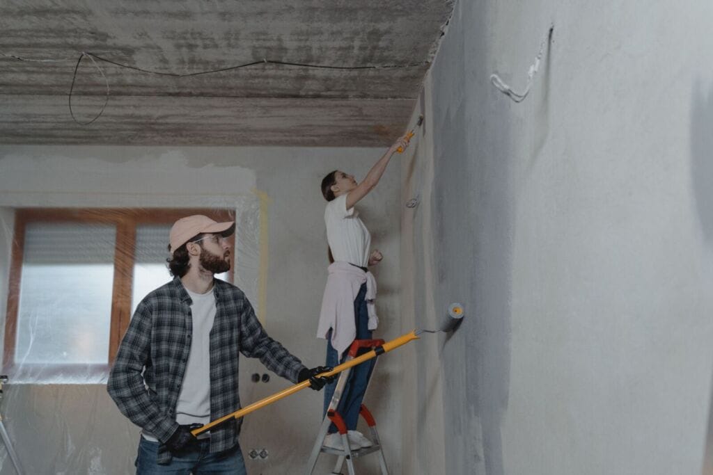 A man and a woman painting the wall.