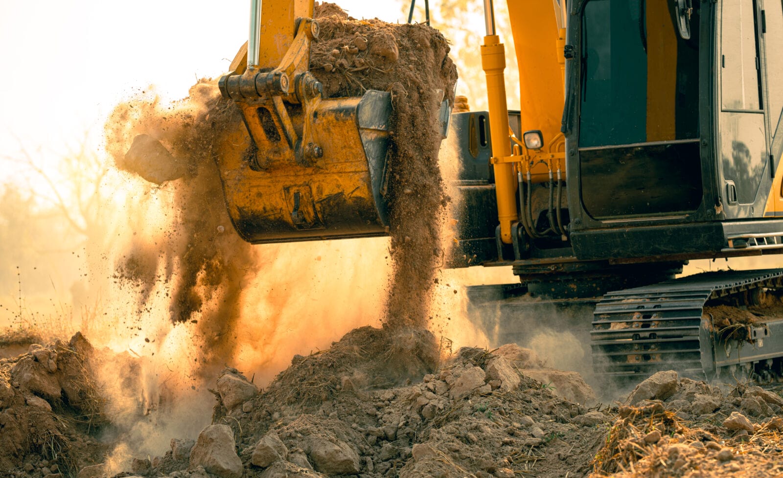 Close-up of excavator at construction site. Backhoe digging soil for earthwork and construction business. Excavating machine at work. Heavy machinery for earth moving and construction site development.